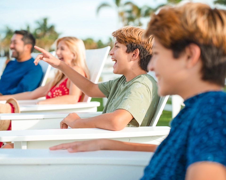 two kids and their parents lounging on beach chairs enjoying their day.