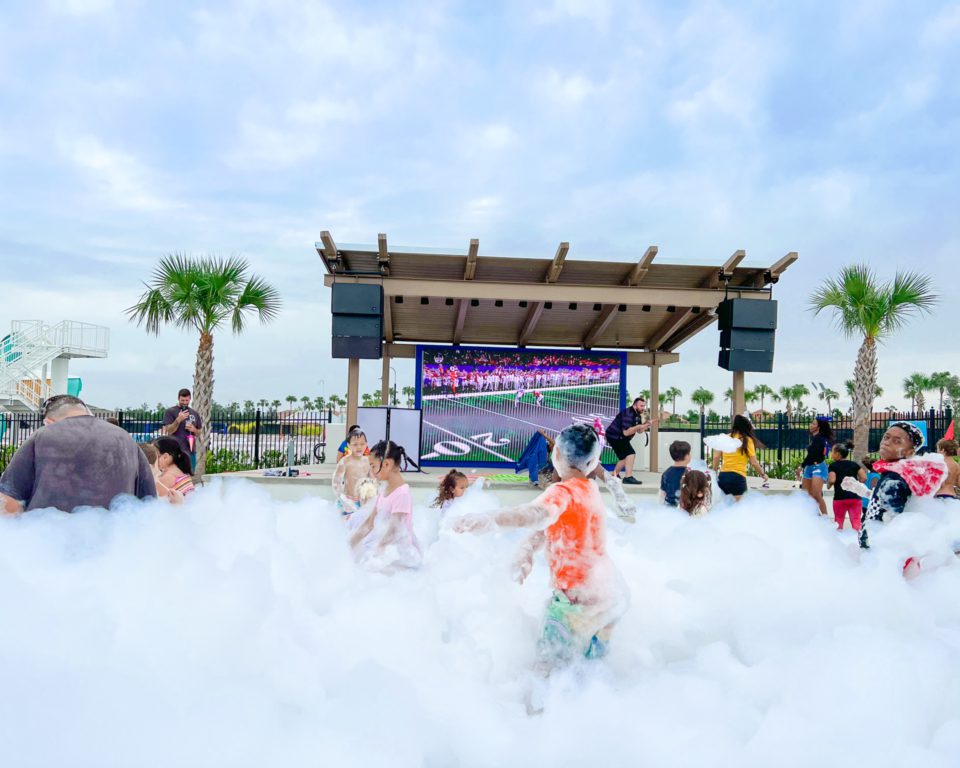 Kids on the turf playing and dancing in a cloud of foam at a foam party